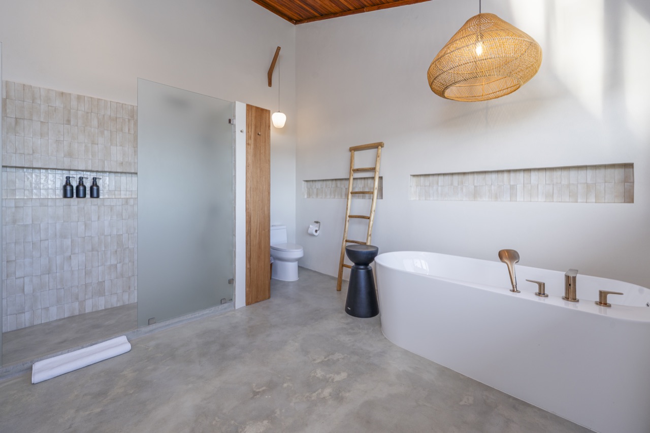 Bathroom with a freestanding bathtub, tiled shower and woven pendant light